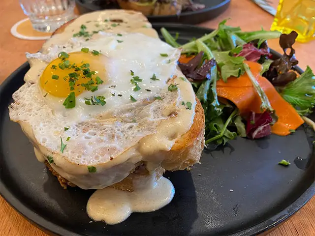 french toast with egg and salad plated on a black plate