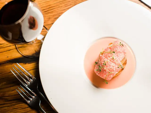 fish with sauce plated on a round plate served with wine